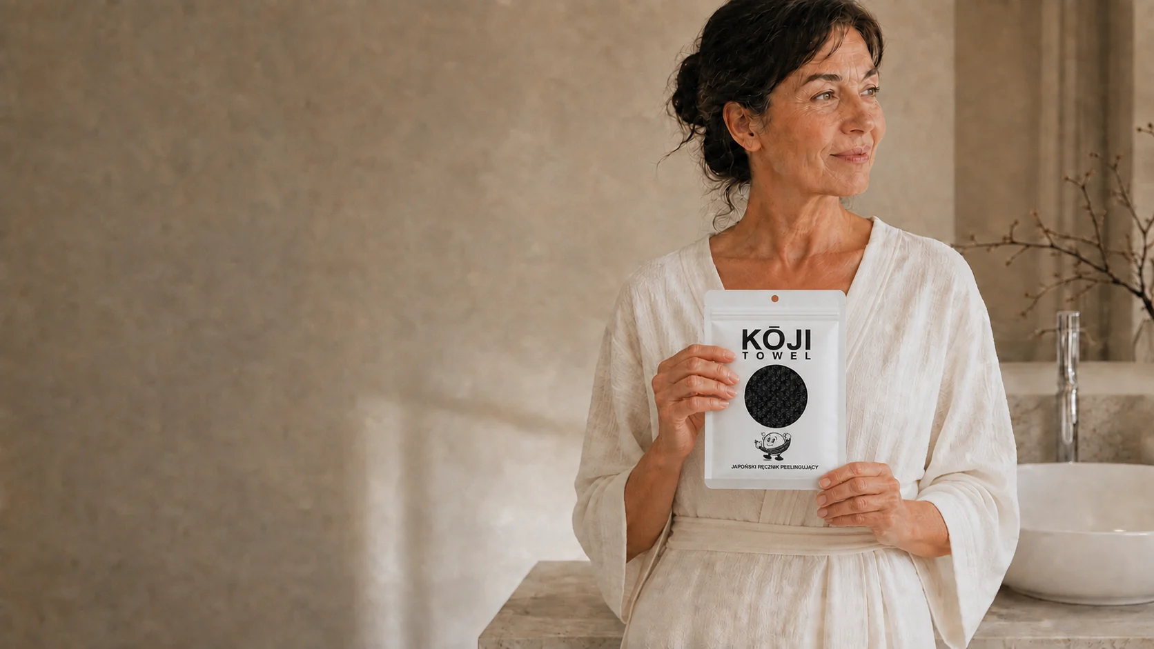 Kobieta trzyma opakowanie Kōji Towel w jasnej łazience