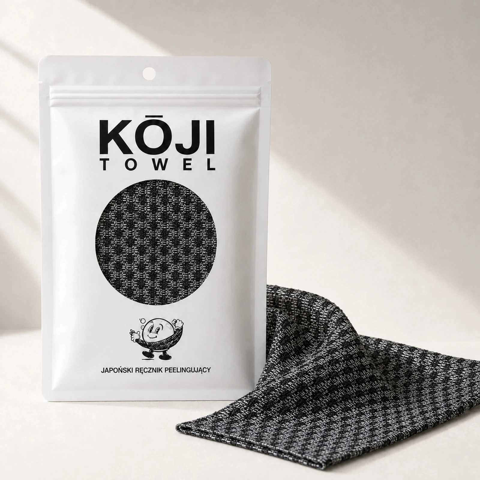 Opakowanie Kōji Towel obok złożonego ręcznika